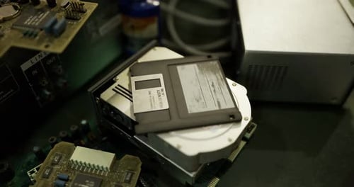 Old Computer Hardware and Floppy Disk on a Workbench in a Workshop