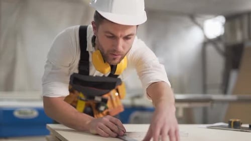 Construction Worker Measures Wood with Ruler in Workshop