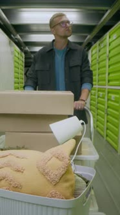 Vertical d'un homme organisant ses affaires dans une installation d'entreposage en libre-service vert vif