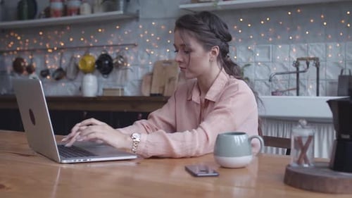 Woman Working on Laptop at Kitchen Table