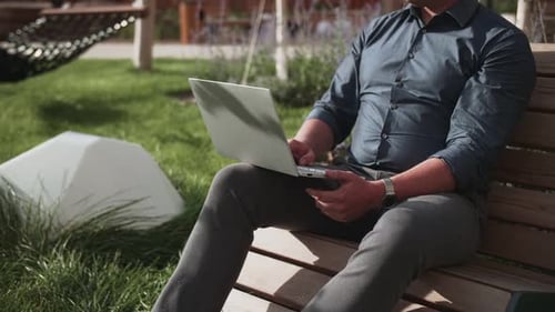 a man works at a laptop in a park