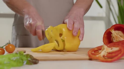 Person Slicing Yellow Bell Pepper with Knife