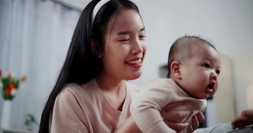 Smiling Woman Holds Infant Playing with Toy