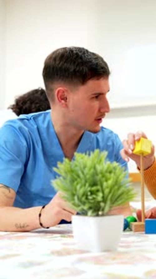 Nurse Assisting Elderly Woman Playing with Building Blocks