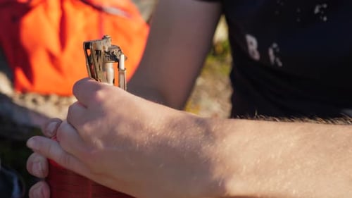 Close up profile shot of person opening metal pan holder on a orange propane camping fuel heater, ou