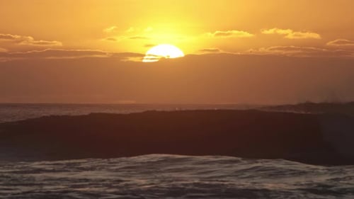 Bright Sun Goes Down Behind a Cloud During Orange Sunset Above the Sea