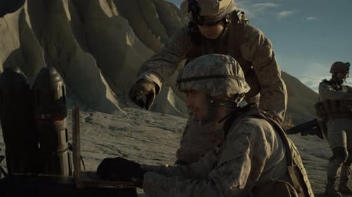Soldiers review laptop in desert combat setting