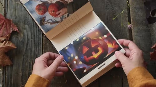 Álbum de fotos con fotografías impresas de Halloween, manos navegando por el álbum de fotos