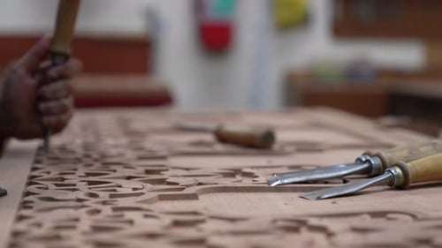 Woodworker Hand Carving Ornate Design with Chisel and Hammer