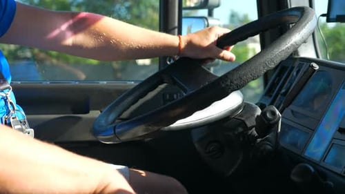Unbekannter Fahrer hält seine Hand am Lenkrad und fährt Lastwagen auf der Landstraße bei Sunny