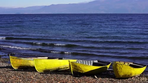 Yellow fishing boats on shore of waving lake with blue water at beautiful sunrise In Autumn morning