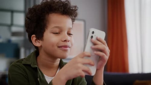 Young Boy Using Cellphone Indoors, Smiling