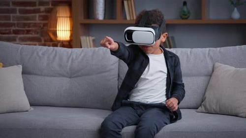 Excited boy wearing VR headset on sofa indoors