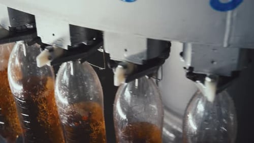 Rotating Bottle Filling Machine Pouring Lemonade into PET Bottles