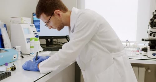 Man in Lab Coat Writes in Scientific Laboratory