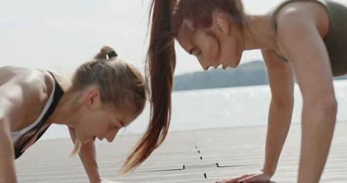 Two Young Women Doing Pushups on Dock