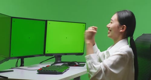 Woman Working at Computer Celebrates in Green Screen Office