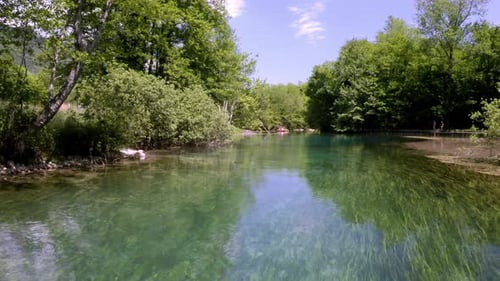 drone moving close to a river with two canoes near to a forest