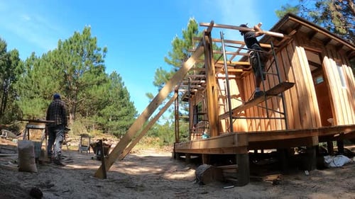 Time lapse shot of two men build a wooden house in the forest. Installing the roof braces. Self-cons