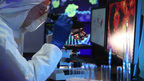 Man in biological protection works in the laboratory with a microscope.