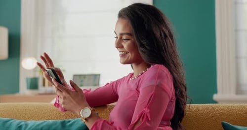 Smiling Woman Uses Smartphone Relaxing on Couch at Home