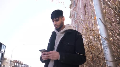 Young Man Using Smart Phone Below Urban Building Adult