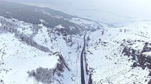 Aerial View of Vehicles Driving on a Snow Covered Mountain Road