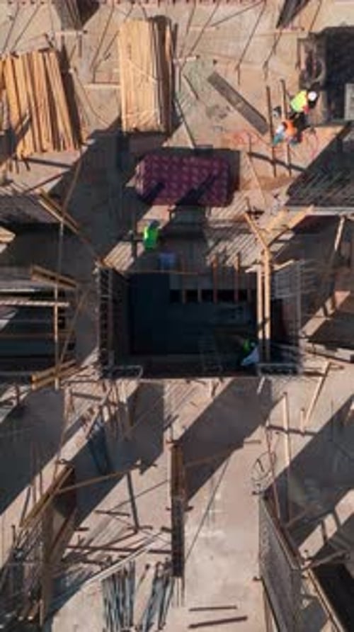 Vídeo vertical: Un sitio de construcción activo presenta a trabajadores colocando ladrillos y construyendo paredes con habilidad