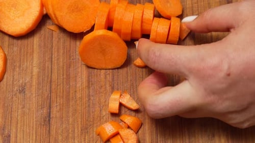 Close Up of Hands Chopping Carrots on Board