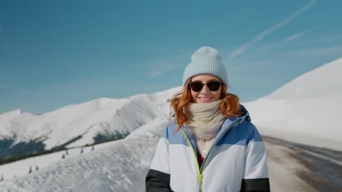 Lonely female trekker dressed jacket walking by snowy slope footage in mountains.