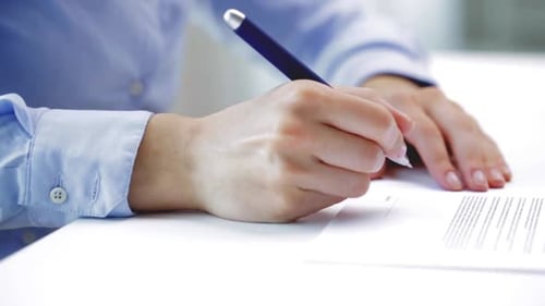 Woman Signing Document on Desk in Office