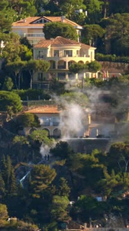 Smoke coming out of the town Villefranche-sur-Mer on the French Riviera. Vertical