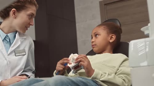 Friendly Dentist Talking to Child Patient About Teeth