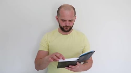 Bald Man in Yellow Shirt Reading Notes and Contemplating Indoors During Daytime