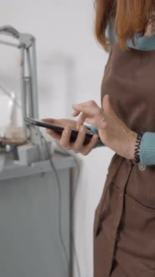 Crop View Of Young Artisan Browsing On Her Smartphone Inside Her Working Place Medium Shot