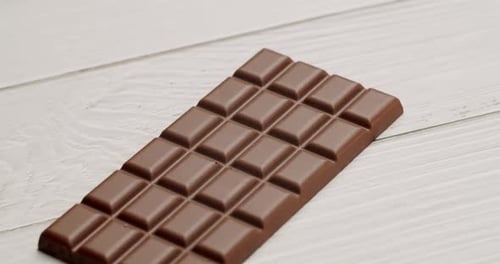 Delicious Milk Chocolate Bar on White Wooden Background