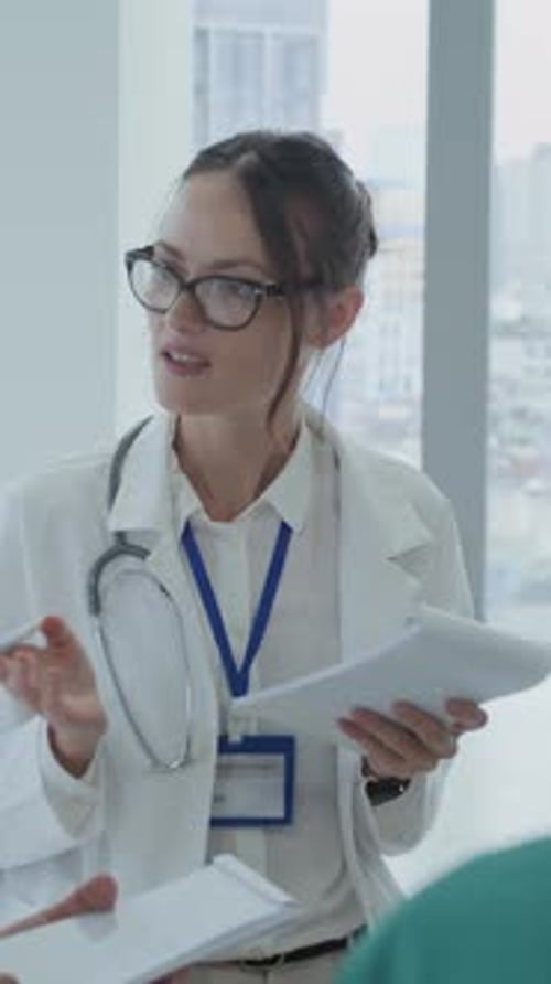 Female Doctor Talking to Colleagues during Meeting at Clinic