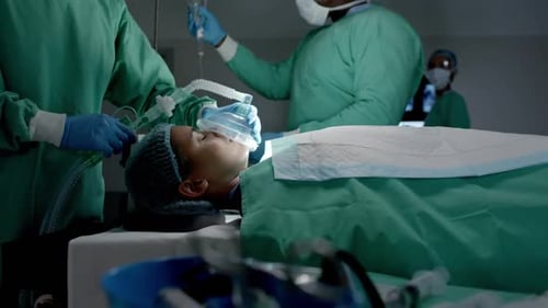 Verschiedene Chirurgen mit Gesichtsmasken und Sauerstoffmaske am Patienten im Operationssaal in Zeitlupe