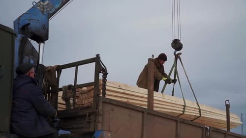 Workers Unloading Lumber from Truck Using Crane