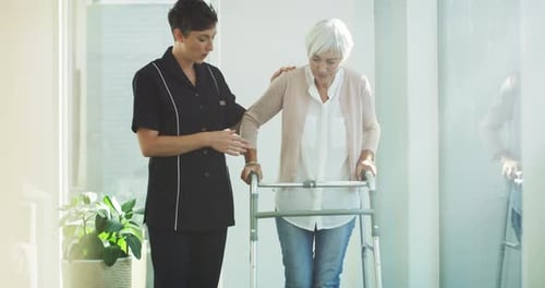 4k video footage of a young nurse assisting a senior woman walk using her walker at a nursing home