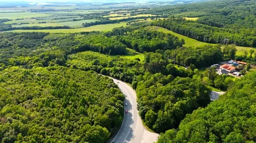 Winding road in green hills. A winding road passes through lush forests and fields