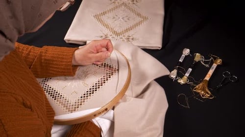 Woman Hand Embroidering a Floral Design with Gold Thread