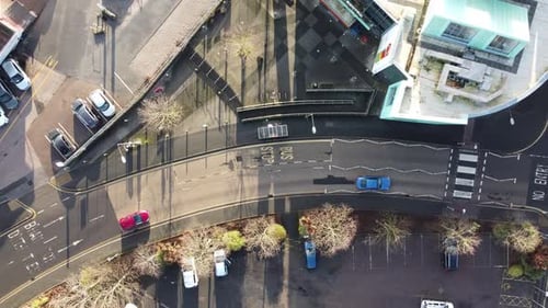 A still, top down shot, of a curved road, with a steady flow of cars passing through the frame.