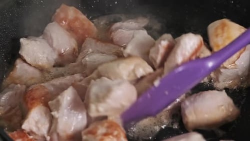 Pieces of Chicken Meat are Fried in a Frying Pan in Home Kitchen