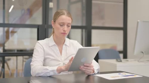 Mature Business Woman Celebrating Success on Tablet in Office