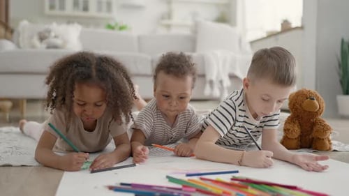 Children Drawing Together on Floor Indoors