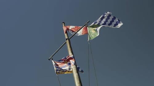 The flags of Canada, British Columbia and Vancouver on a mast waving in the wind, slow motion handhe