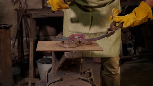 A Blacksmith Man Making a Metal Fence He Knocks with a Hammer on Hot Metal