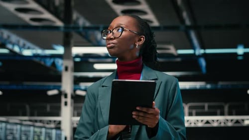 Tablet zum Debuggen von Systemen und Ingenieurin, die im Rechenzentrum spazieren geht