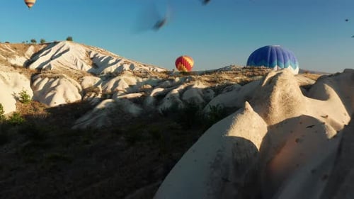 Flying through landscape of Turkey as flock of birds pass with hot air balloon in background